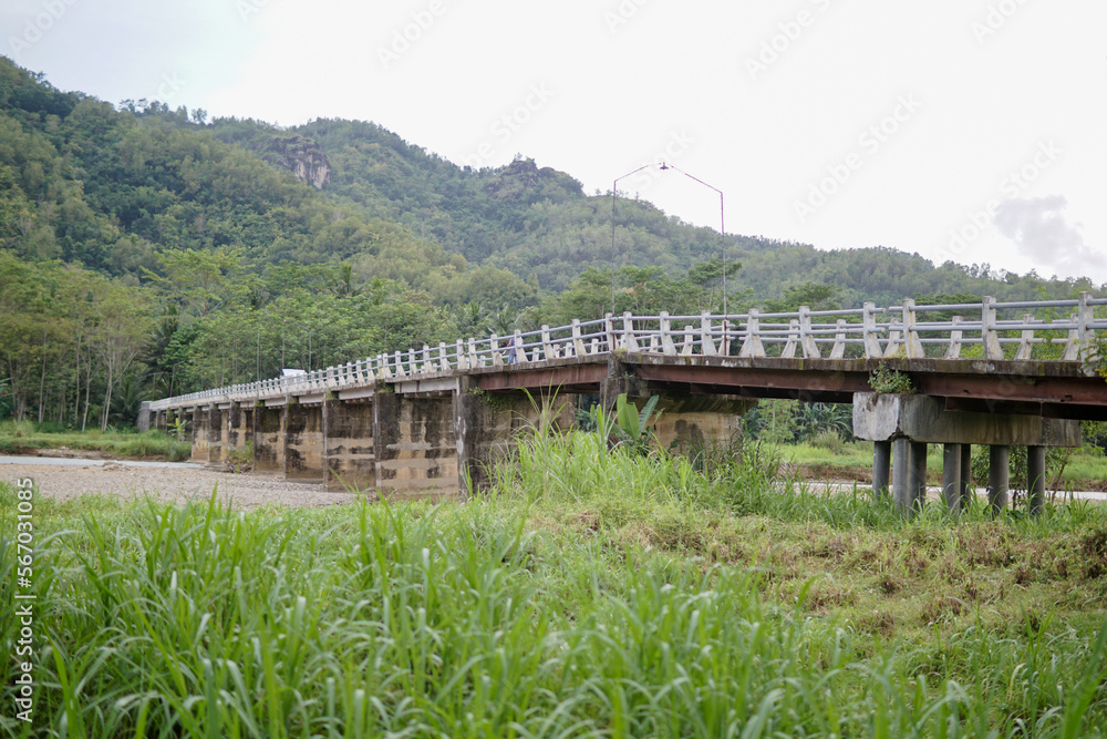 a bridge crossing people from village to village with a view of the river and green mountains a bridge crossing people from village to village with a view of the river and green mountains