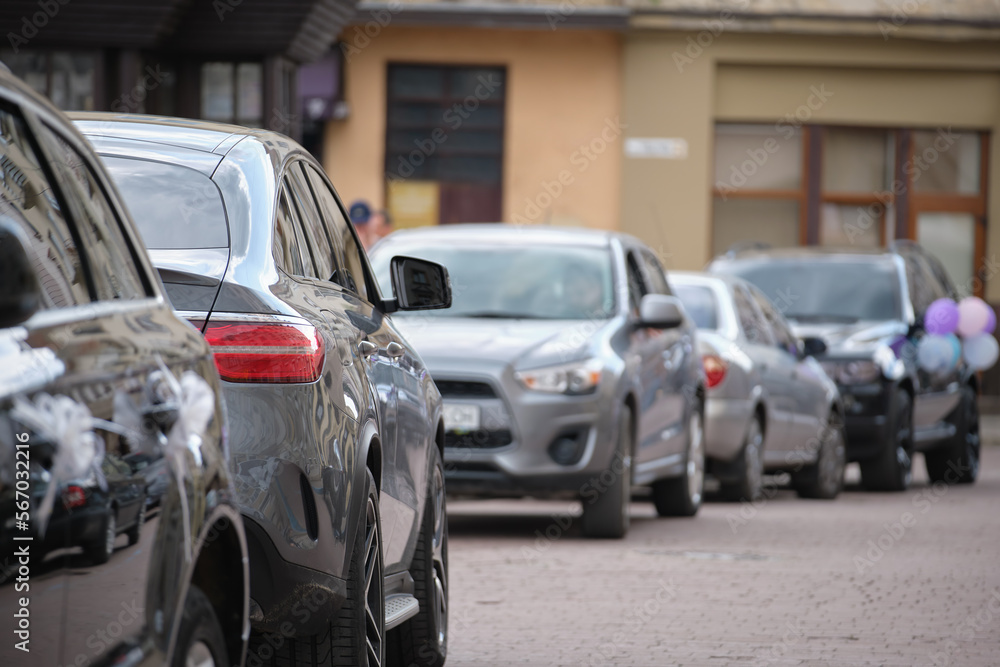 Naklejka premium Cars parked in line on city street side. Urban traffic concept