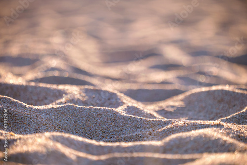 Close up of clean yellow sand surface covering seaside beach illuminated with evening light. Travel and vacations concept