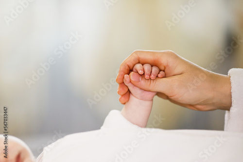 Close up mother holding tiny hand of little newborn baby boy girl, helping hands, bonding different generations. Happy motherhood concept.