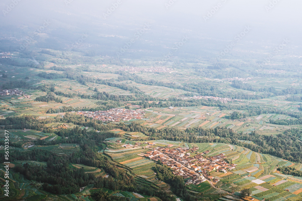 Pattern aerial view of a remote village surrounded with green terrace agricultural farm field in Magelang, Indonesia
