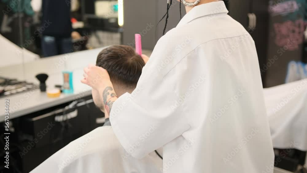 A professional stylist in a modern stylish barber shop cuts the hair of a young man Beauty salon, hairdresser. A professional stylist in a modern stylish barber shop cuts the hair of a young man Beauty salon, hairdresser.