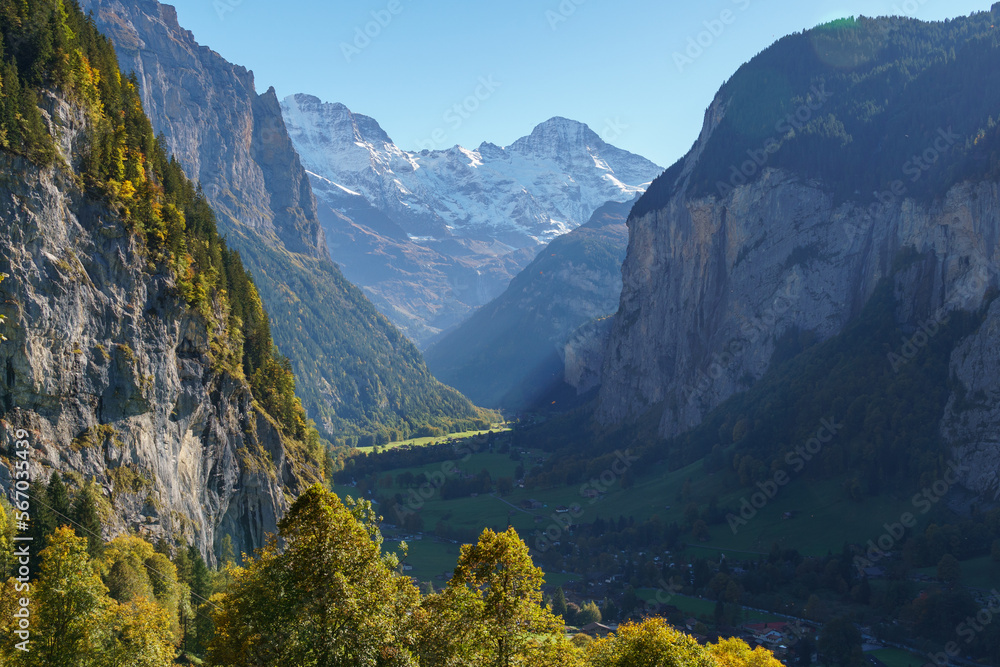 Steep alpine mountains descend to a shadowy valley and the town of Lauterbrunnen