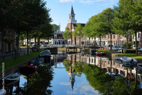 The historic city center of Weesp, a small town located in the East of Amsterdam, North Holland, Netherlands, with reflections of historic houses and boats on the Oudegracht canal 
