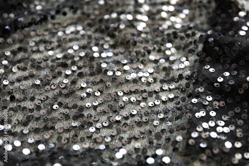 defocused black and silver knitted fabric with sequins and folds texture background 