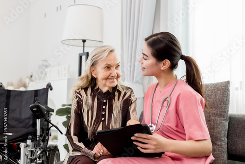 Pleasant confident skilled blond woman doctor in glasses and white coat, visiting patient, senior lady, at home for treatment control, handshaking and giving recommendations. Healthcare concept
