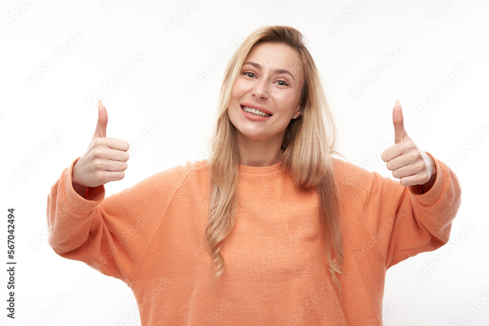Happy blonde girl shows hand with thumbs up and smiles at the camera isolated on white background Happy blonde girl shows hand with thumbs up and smiles at the camera isolated on white background