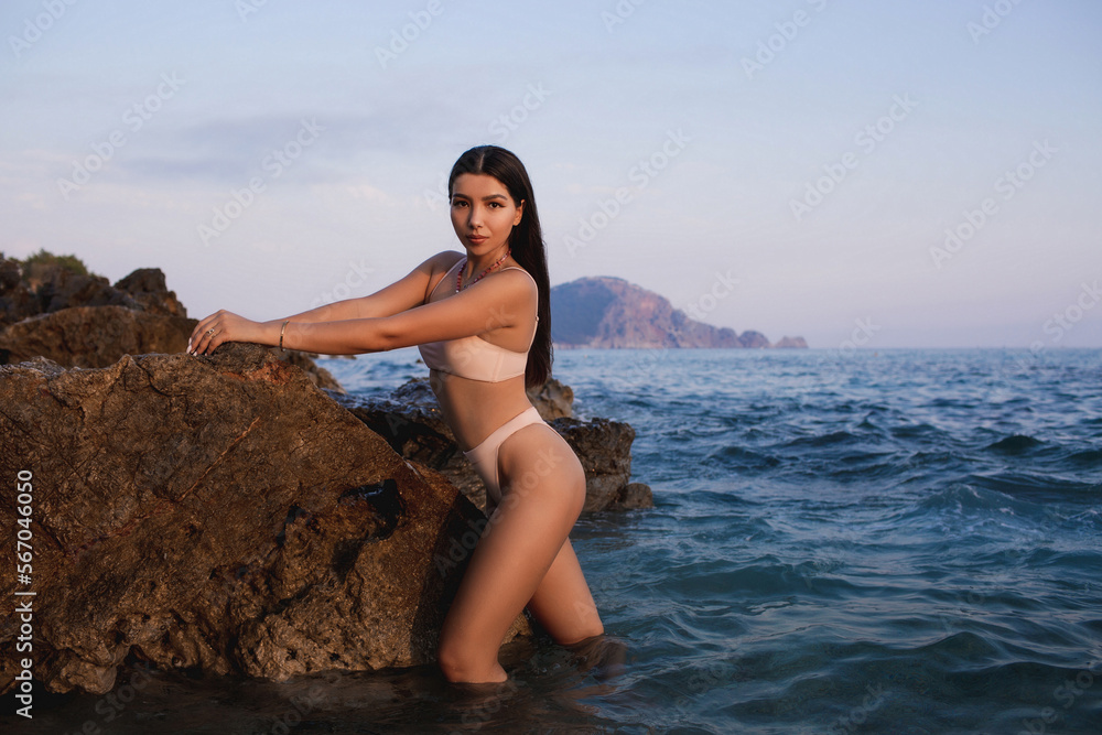 Brown-eyed girl with long hair in a beige bathing suit on the seashore. Brown-eyed girl with long hair in a beige bathing suit on the seashore.