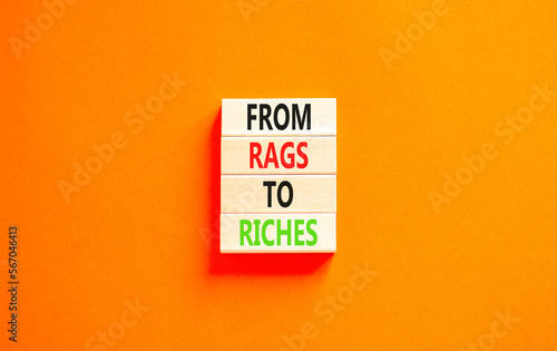 Rags or riches symbol. Concept words From rags to riches on wooden blocks. Beautiful orange table orange background. Business rags or riches concept. Copy space.