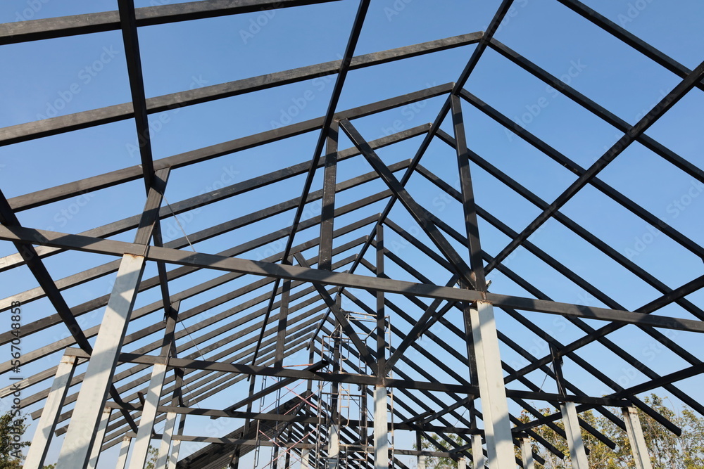 Steel roof structure. Detail of black steel truss structure for building construction on blue sky background and selective focus.