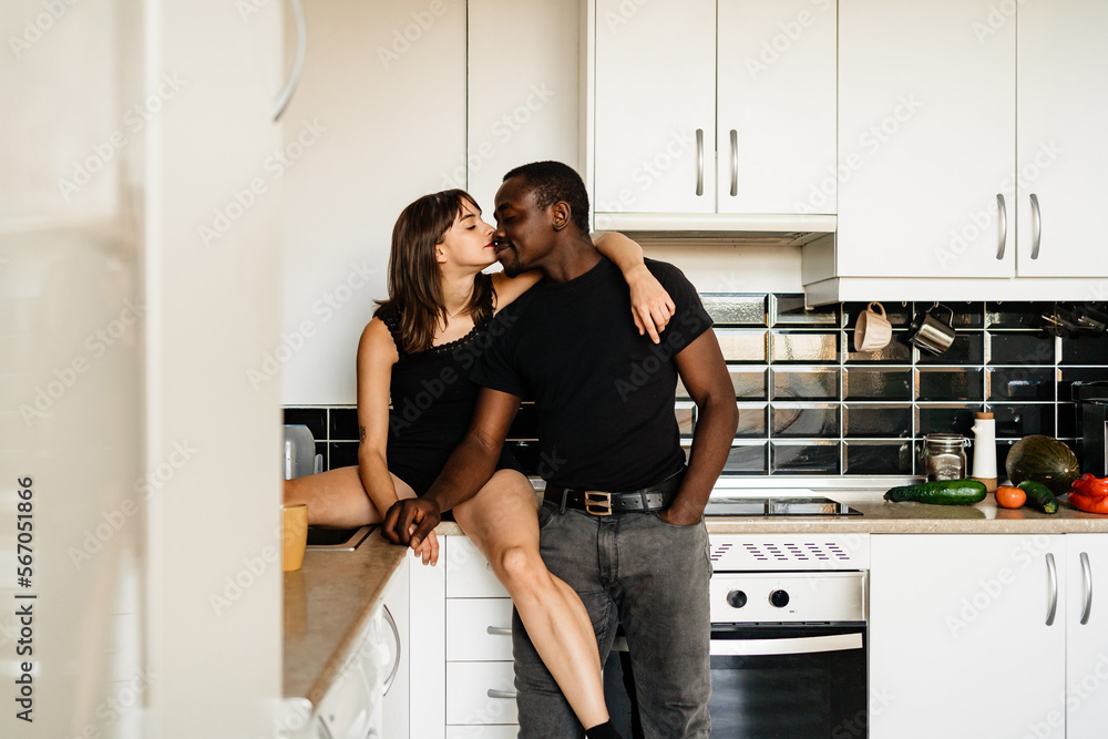 Romantic diverse couple kissing in kitchen Romantic diverse couple kissing in kitchen