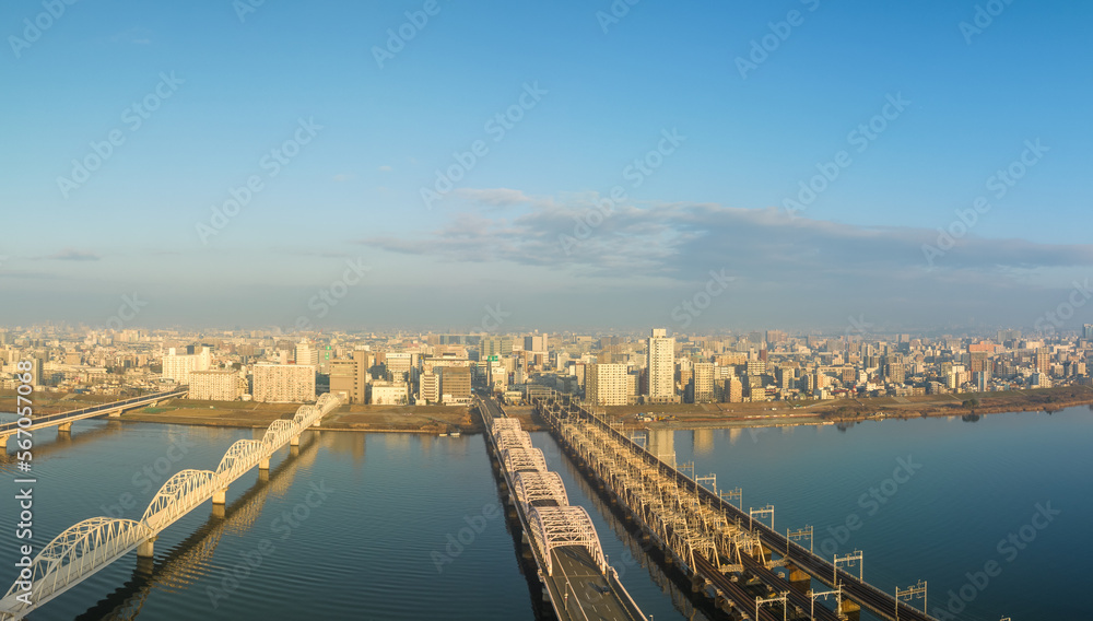 Vehicle bridge next to train bridge over wide river next to city after sunrise Vehicle bridge next to train bridge over wide river next to city after sunrise
