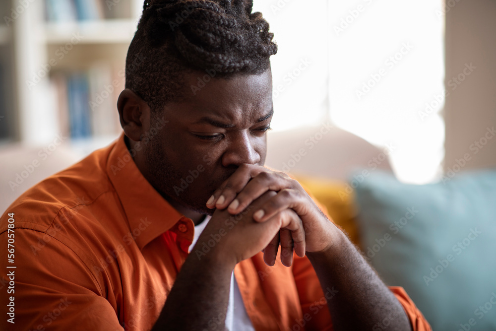 Depressed black guy sitting alone on couch at home, closeup Depressed black guy sitting alone on couch at home, closeup