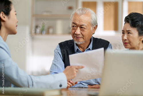 senior asian couple appears to be unconvinced and confused while listening to a saleswoman