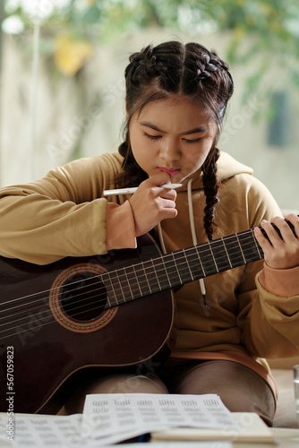 Talented pensive girl creating new song, writing down music notes