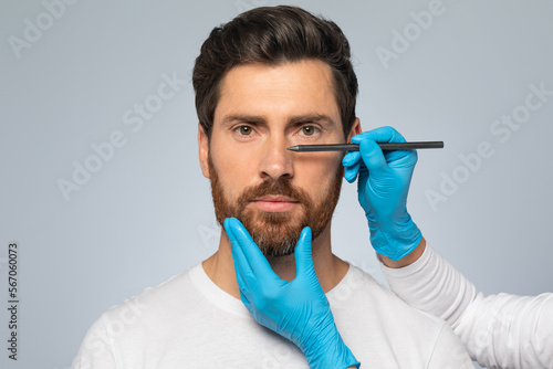 Fotografija Doctor making marks on male patient's face, middle aged man on consultation at s