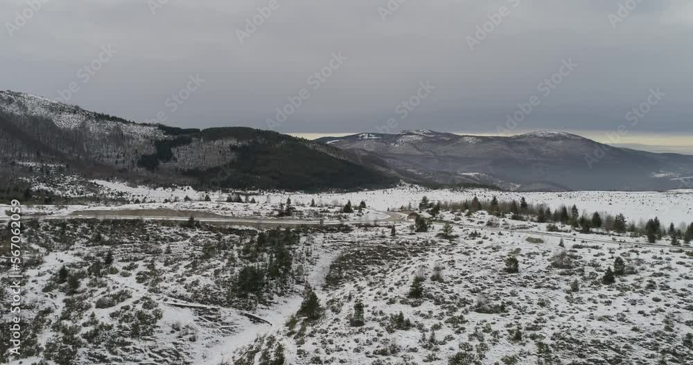 Aerial view of mountain twisted road in the winter. Epic, snowy white winter in the mountains. High rocky mountains and clean road through frozen forest. Aerial view of mountain twisted road in the winter. Epic, snowy white winter in the mountains. High rocky mountains and clean road through frozen forest.