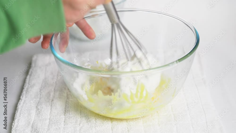 Male chef mixes whipped meringue protein with egg yolk and flour dough with a hand whisk. High quality 4k footage Male chef mixes whipped meringue protein with egg yolk and flour dough with a hand whisk. High quality 4k footage