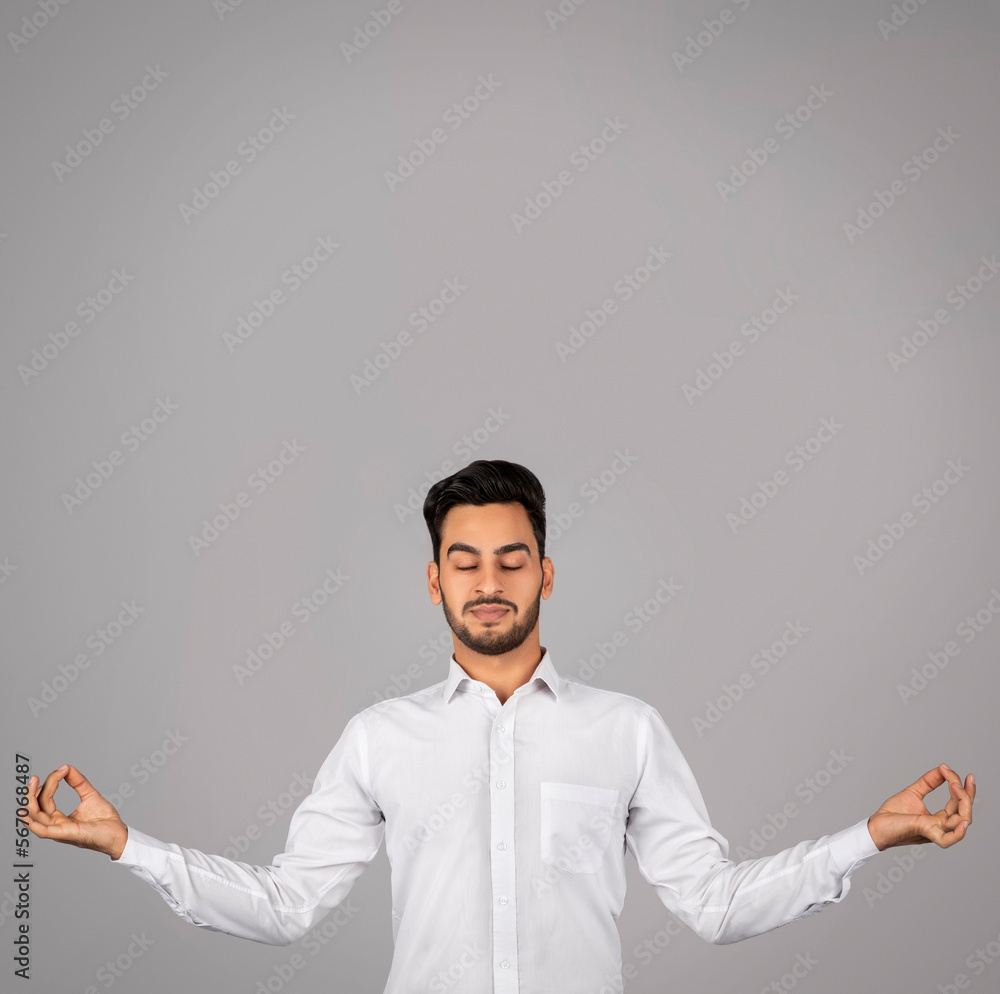 Zen Concept. Calm Arab Businessman Meditating Over Grey Background Zen Concept. Calm Arab Businessman Meditating Over Grey Background