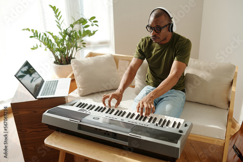 Photography Creative man playing synthesizer in his apartment enjoying good music