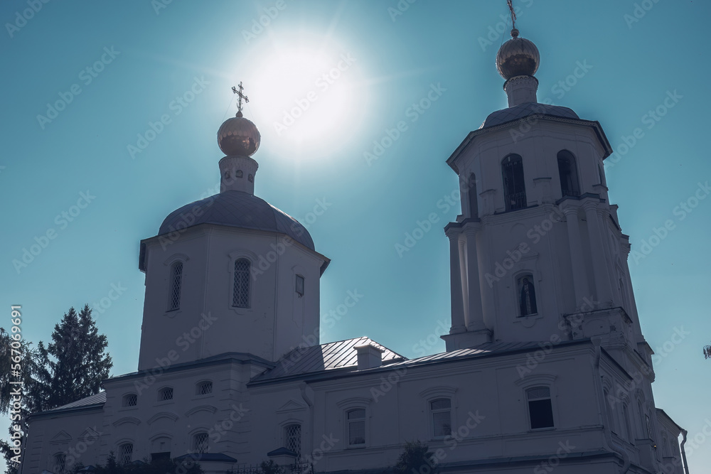 Exterior of old Orthodox Spassky church in Solnechnogorsk. Gilded domes against the background of the sun and blue sky