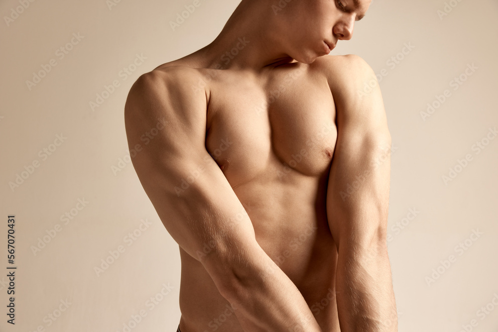Young male model posing in underwear. Cropped image of muscular relief body, breast over grey studio background. Concept of men's health and beauty, body and skin care, fitness. Body art Young male model posing in underwear. Cropped image of muscular relief body, breast over grey studio background. Concept of men's health and beauty, body and skin care, fitness. Body art