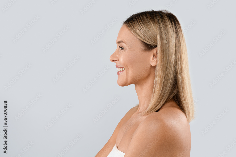 Profile portrait of middle aged blonde woman isolated on grey Profile portrait of middle aged blonde woman isolated on grey