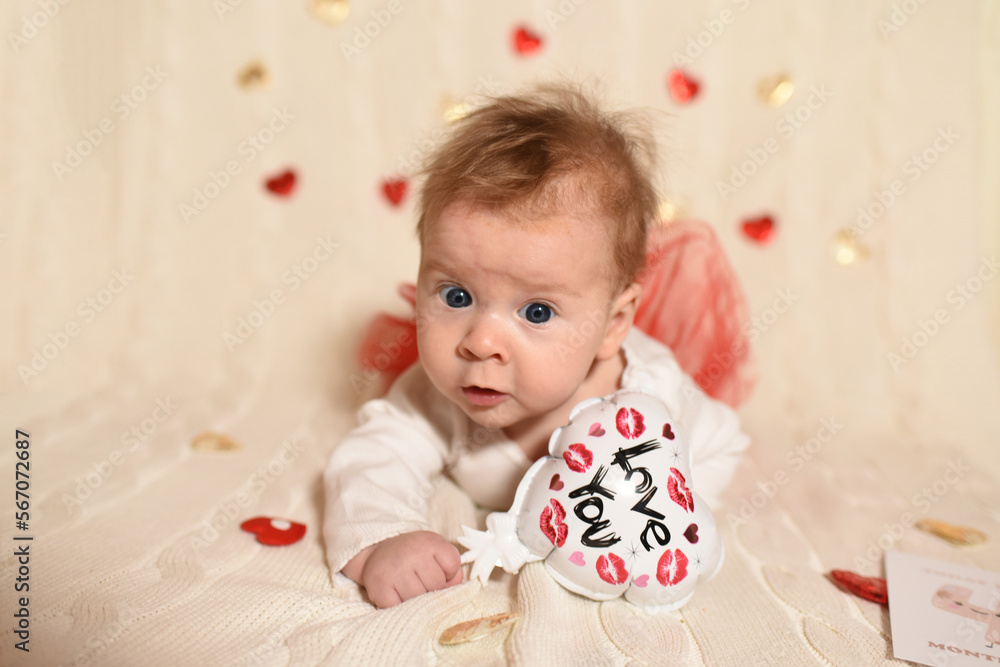 Little baby 4 months old. Valentine's Day. The kid holds a heart. Beautiful baby on light background Little baby 4 months old. Valentine's Day. The kid holds a heart. Beautiful baby on light background