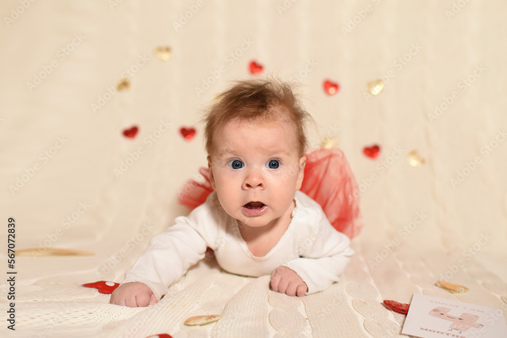 Little baby 4 months old. Valentine's Day. The kid holds a heart. Beautiful baby on light background