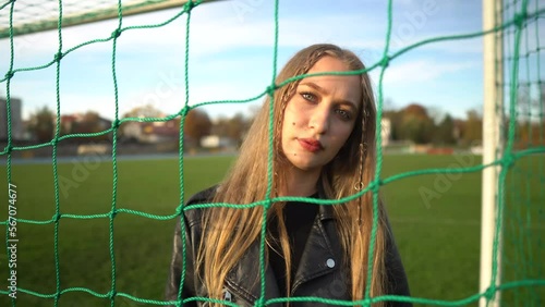 Portrait of young serious girl looking into camera in soccer gate at sport field