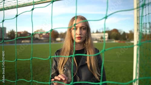Portrait of young serious girl looking into camera in soccer gate at sport field