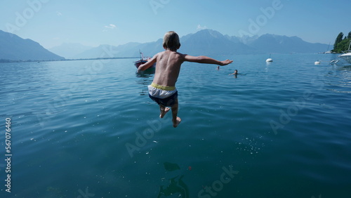 One carefree young boy running on pier and jumping into water lake