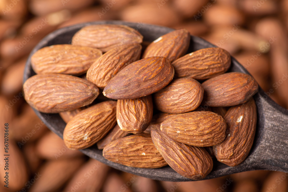 Macro shot of tasty almond nuts in dark wooden spoon. Cooking with almond concept, tasty fresh nuts Macro shot of tasty almond nuts in dark wooden spoon. Cooking with almond concept, tasty fresh nuts
