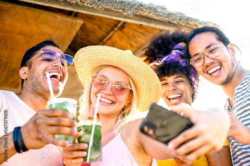 Multi racial friends taking a selfie at the beach - Group of young people toasting with mojito at kiosk in the summertime - Holidays, fun, happy lifestyle concept photo