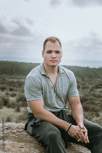 Young Male Model Sitting on Rock Cliff after Hiking. Sporty Portrait