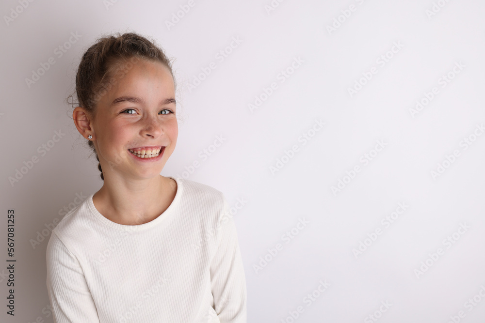 Little emotional teen girl in white shirt 11, 12 years old on an isolated white background. Children's studio portrait. Place text, to copy space for inscription, advertising children's goods.