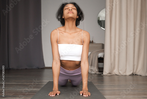 Front view on happy african amercian gifrl prscticing yoga at home. Banner with place for text