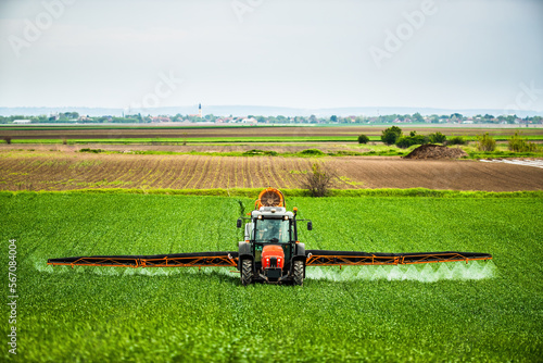 Herbicide, pesticide, and fungicide application in wheat fields with tractor, farmer protecting crops from pests and diseases photo