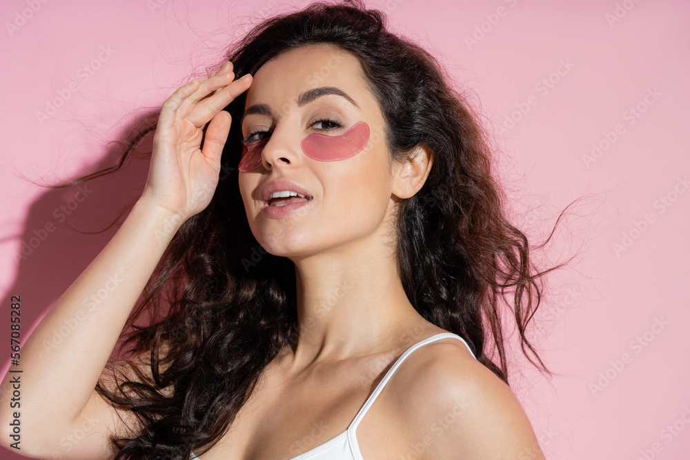 Pretty woman with hydrogel eye patches touching forehead on pink background. Pretty woman with hydrogel eye patches touching forehead on pink background.