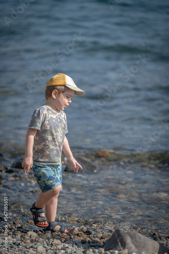 Niño con gorra caminando jugando con agua a orillas de un lago