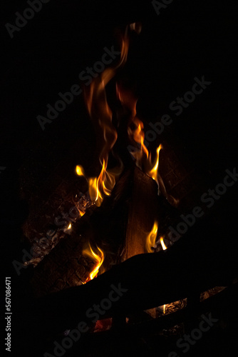 Tongues of yellow-hot flame in the dark room. Tongues of flame. Black background. Fire in the fireplace. Crackling logs. Home comfort. Heating in winter.
