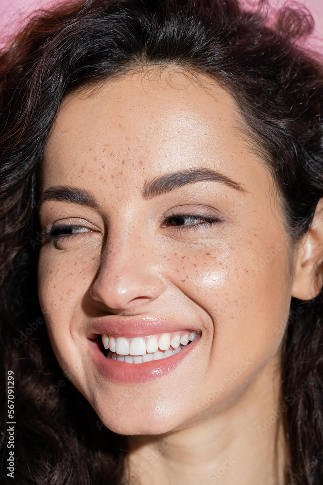 Portrait of smiling woman with freckles looking away isolated on pink. Portrait of smiling woman with freckles looking away isolated on pink.