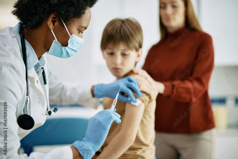 Black female doctor vaccinating small boy at medical clinic. Black female doctor vaccinating small boy at medical clinic.