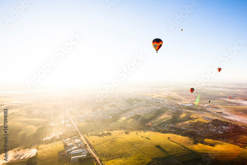 Hot air balloons flying over landscape against clear sky during sunny day photo