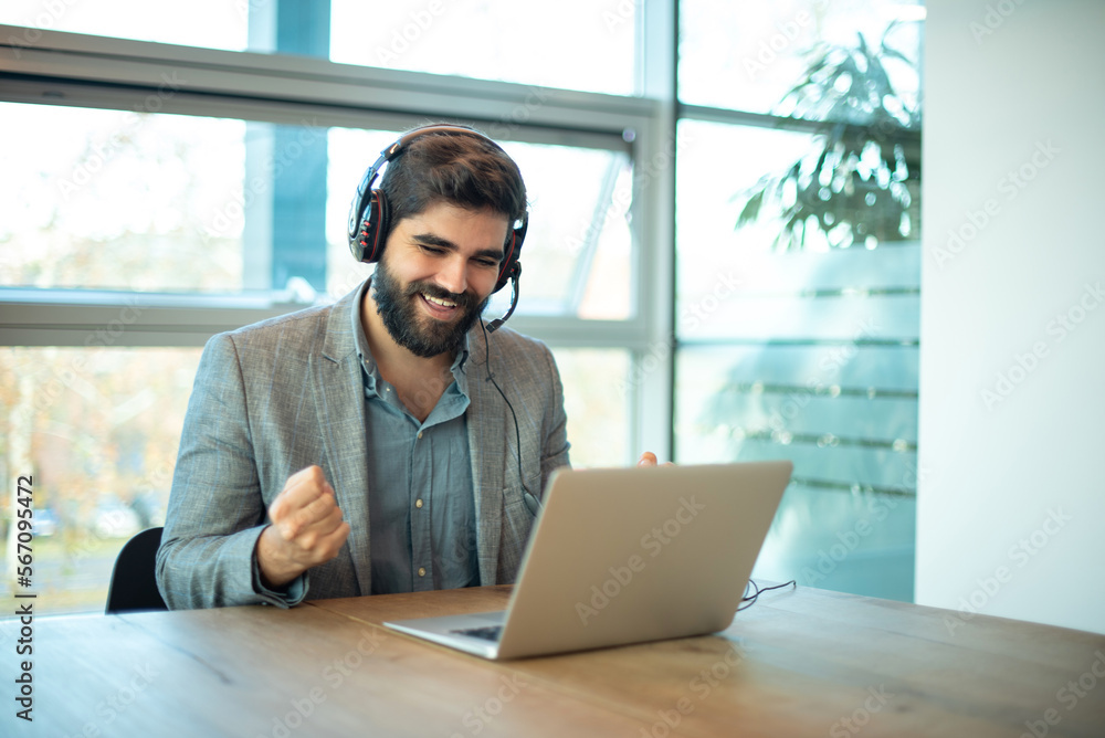 Euphoric male telephone worker with headset celebrating a good job in his workplace Euphoric male telephone worker with headset celebrating a good job in his workplace