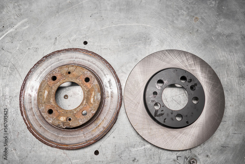 Old rusty brake disc and new disc. Change the old to new brake disc on car in a garage. Auto repair concept. photo