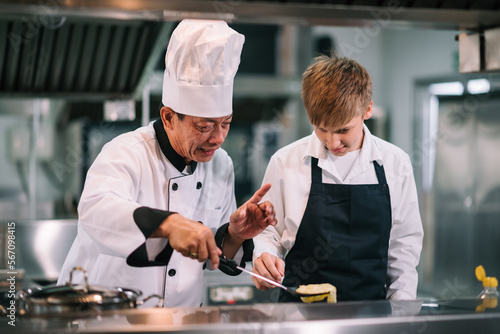 Mature asian teacher teaching schoolboy chef students to select ingredient for cooking in class.