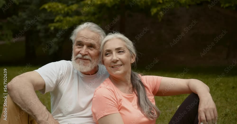 Joyful aged couple talking in the park after sport activities Joyful aged couple talking in the park after sport activities