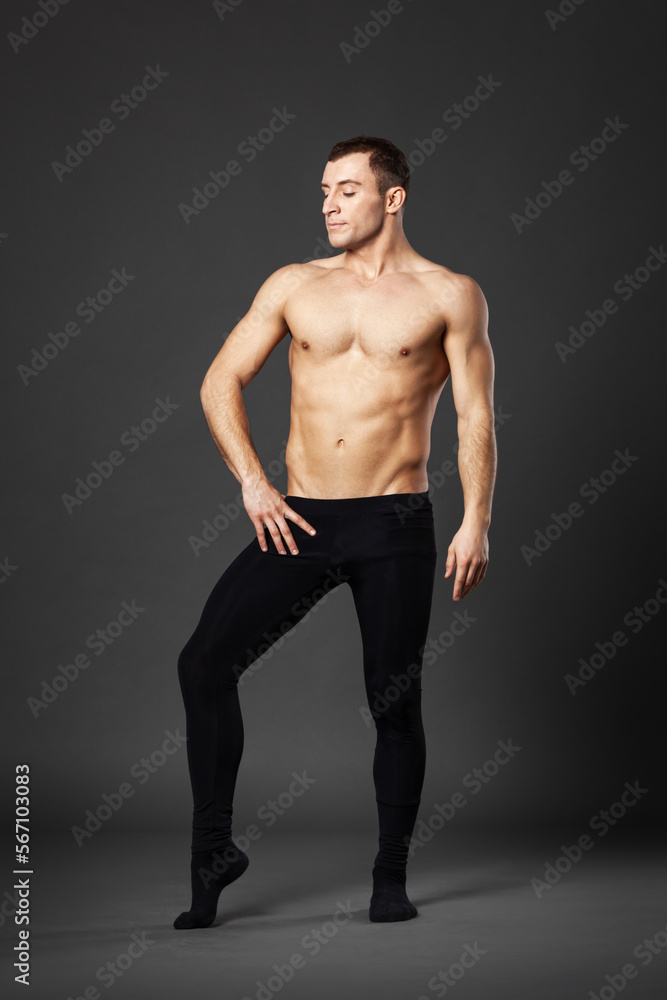 Full body portrait of a young ballet dancer posing on a gray background.