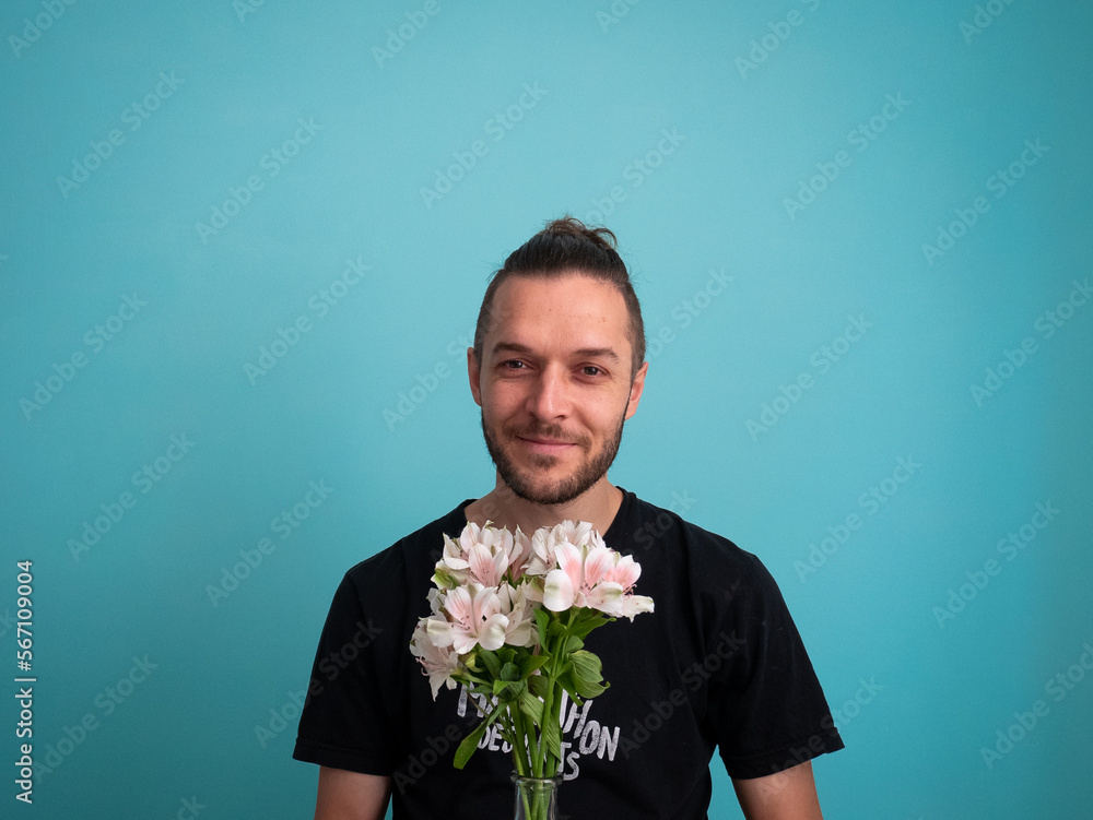 White Man Smiling and Holding Flowers on a Turquoise Background White Man Smiling and Holding Flowers on a Turquoise Background
